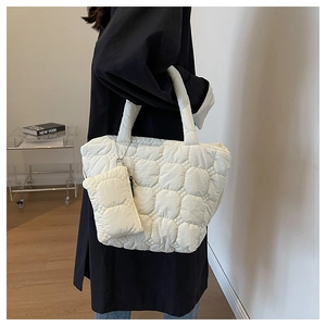 Detailed side view of a white quilted tote bag with a matching mini pouch charm
