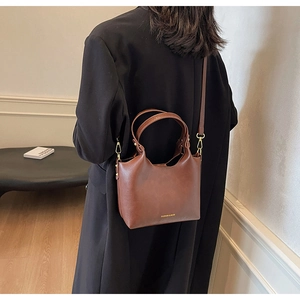 Sac à main vintage en cuir marron avec lettrage doré porté par un mannequin chic