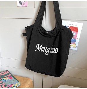 Detail of minimalist black tote bag with white Menghuo lettering and soft texture