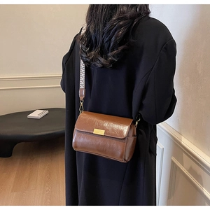 Retro brown leather crossbody bag with geometric woven wide strap on black coat