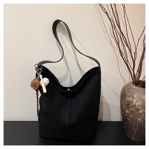Detail einer großen schwarzen Hobo-Tasche mit sportlichem Baseball-Anhänger-Zubehör