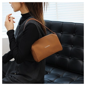 Vue détaillée d'un sac oreiller en cuir marron avec lettrage blanc et fermeture éclair