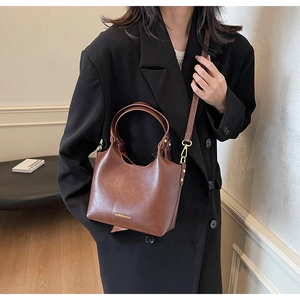 Détail d'un sac seau marron avec ferrures dorées et logo de mode sur le devant