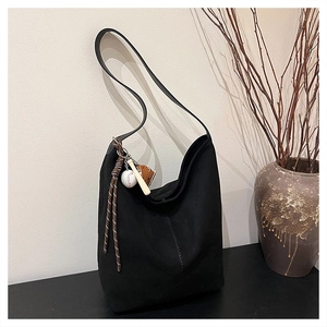 Detail der schwarzen Hobo-Beuteltasche aus Wildleder mit V-Nähten und Baseball-Anhänger