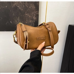 Detail of caramel brown pillow bag featuring textured PU leather and vintage gold hardware
