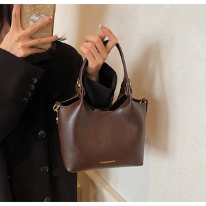 Gros plan détaillé du sac à main marron foncé avec boucles dorées et logo chic