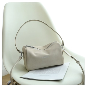 Vue détaillée du sac boston en cuir crème avec des ferrures argentées sur une chaise