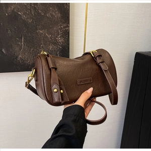 Detail of vintage brown cylinder pillow bag showing high-quality leather texture and gold hardware