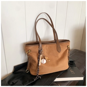 Détail du sac cabas en daim marron avec pendentif baseball et accents de rivets