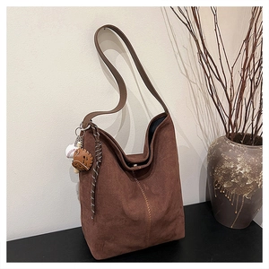 Detailaufnahme der braunen Wildleder-Tragetasche mit Baseball-Anhängern und Ziernaht