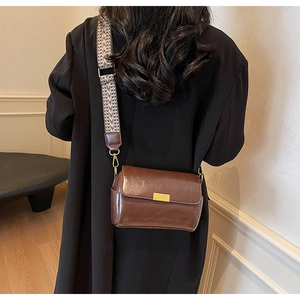 Detail of vintage brown leather crossbody bag with geometric woven strap and gold buckle