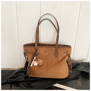 Détail d'un sac cabas en daim marron avec pendentif décoratif de gant de baseball