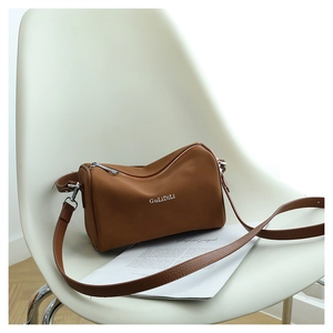 Gros plan détaillé du sac Boston marron sur chaise blanche montrant texture nylon et boucles