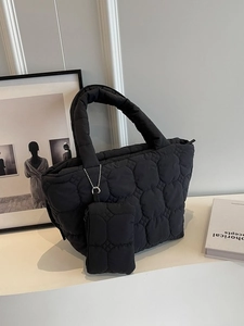 Black quilted puffer tote bag with matching mini pouch in a minimalist urban setting