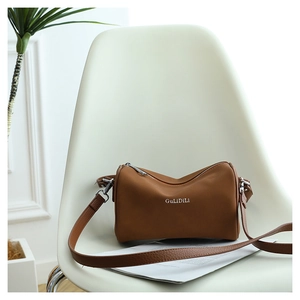 Détail d'un sac polochon en cuir marron avec fermeture éclair argentée et logo blanc