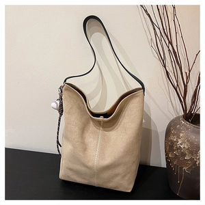 Detail der beige Hobo-Tasche mit Baseball-Anhänger und strukturiertem Wildleder