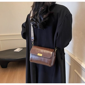 Detail of vintage brown leather crossbody bag with geometric woven wide strap on model