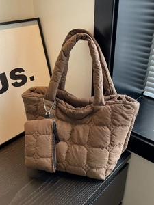 Brown quilted tote bag with matching pouch shown in a stylish minimalist setting