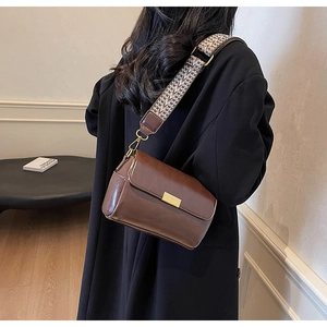 Detail of vintage brown crossbody bag featuring stylish wide woven jacquard strap