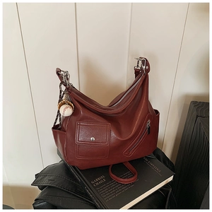 Détail du sac en cuir bordeaux avec poches métalliques et pendentif de baseball