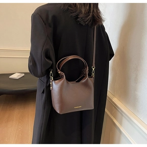 Vue détaillée du sac seau en cuir marron foncé avec accessoires dorés et bandoulière