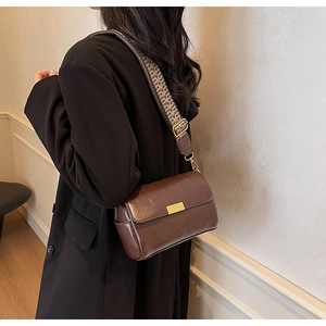 Close-up of retro brown oil wax leather crossbody bag with colorful woven shoulder strap