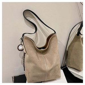 Detail der khakifarbenen Wildledertasche mit Baseball-Anhänger und weißer Naht