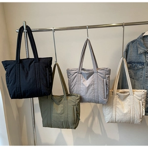 Detail view of large tote bags in black, green, grey and beige showing side zipper pockets