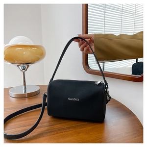 Détail du sac polochon en cuir noir avec fermeture éclair argentée et logo