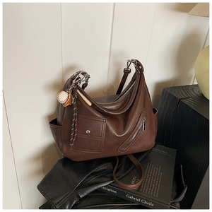 Détail de sac hobo marron foncé montrant la texture du cuir et le pendentif déco