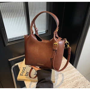 Vue détaillée de la texture du sac en cuir marron avec boucle dorée et logo embossé