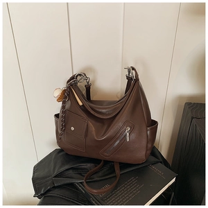 Détail du sac bandoulière marron vintage avec fermeture éclair argentée et porte-clés