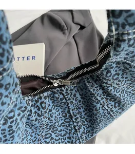 Detail of smooth silver zipper and leopard denim fabric on the shoulder bag