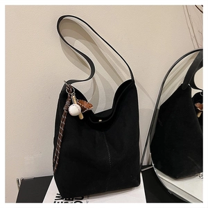 Nahaufnahme der schwarzen Hobo-Tasche aus Wildleder mit dekorativem Baseball-Anhänger