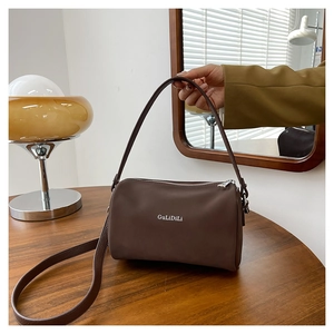Détail d'un sac Boston en cuir marron mat avec logo argenté et fermeture éclair métal