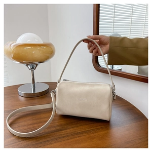 Détail d'un sac Boston beige en cuir mat avec fermeture éclair dorée et bandoulière