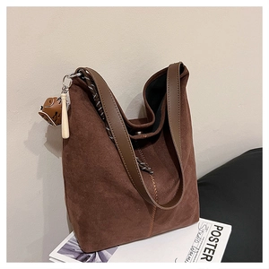 Detail der dunkelbraunen Wildleder-Hobo-Tasche mit handgefertigten Kontrastnähten und Anhänger