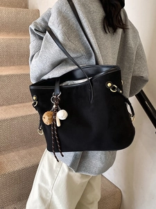 Grand cabas en daim noir avec breloque léopard et boucles dorées porté par une femme