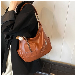 Détail d'un sac Hobo vintage marron avec poches latérales et accessoire de charme baseball