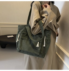 Détail d'un sac cabas en velours côtelé vert foncé avec poches et fermetures à franges