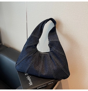Detail of dark blue leopard print denim shoulder bag with white stitching and zipper closure
