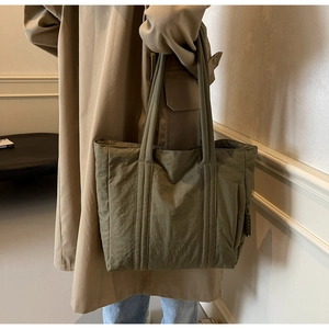 Olive green nylon tote bag shown on a khaki trench coat for a casual autumn style