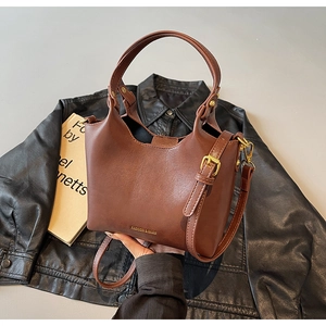 Détail du sac seau marron sur une veste en cuir avec lettrage doré élégant