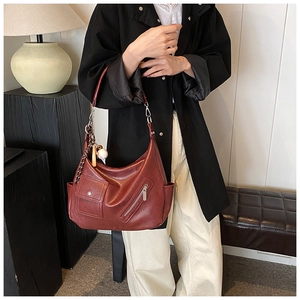 Détail du sac cabas en similicuir marron-rouge avec poches avant et pendentif boule