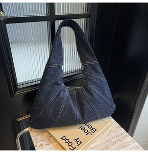 Detail of leopard print denim underarm bag with contrast stitching and zipper closure