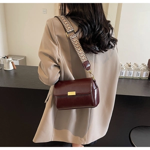Detail view of burgundy leather crossbody pillow bag with vintage wide woven strap