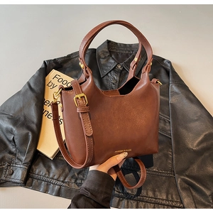 Détail d'un sac seau marron avec lettrage doré et bandoulière réglable pratique