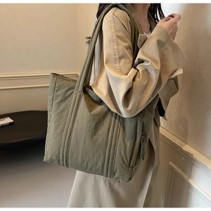Detail of olive green quilted tote bag with long straps and large capacity for commuting