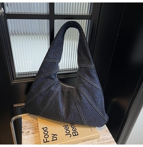 Detailed view of dark blue denim hobo bag with contrast stitching and retro texture