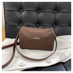 Gros plan détaillé du sac polochon marron mat avec lettrage blanc et bandoulière